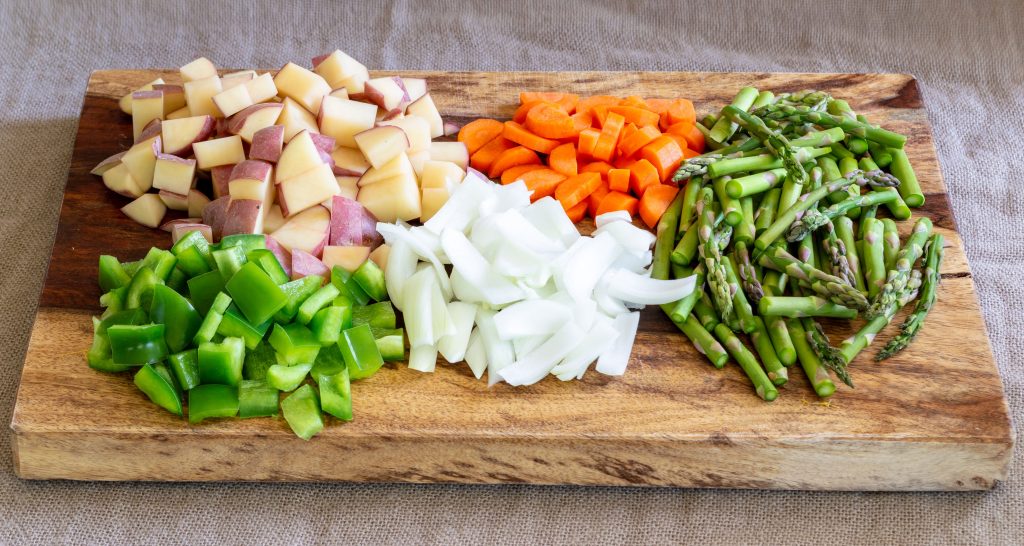 peppers, onion, carrots, onions, and asparagus on a cutting board