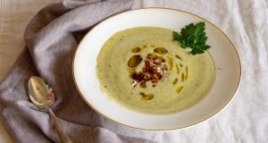zucchini soup garnished with parsley, oil, and pecans.