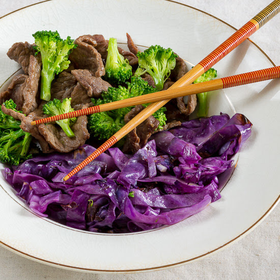 broccoli and beef with purple cabbage in a white bowl with chopsticks