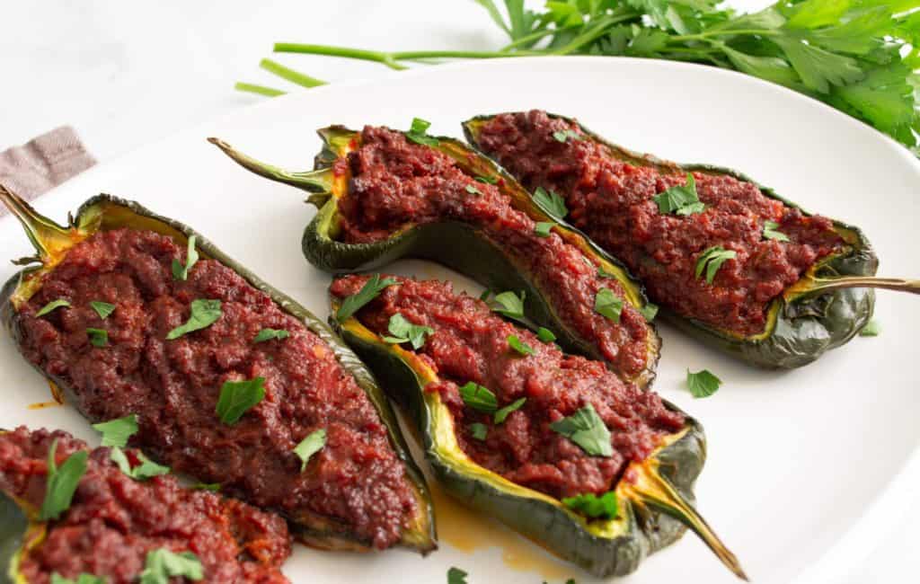 Poblano peppers stuffed with chorizo filling on a white platter, garnished with cilantro.