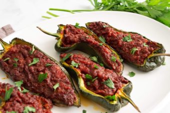 Poblano peppers stuffed with chorizo filling on a white platter, garnished with cilantro.